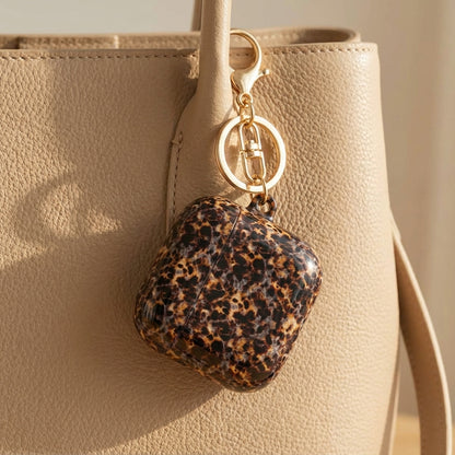 Tortoiseshell AirPod case clipped to a bag strap